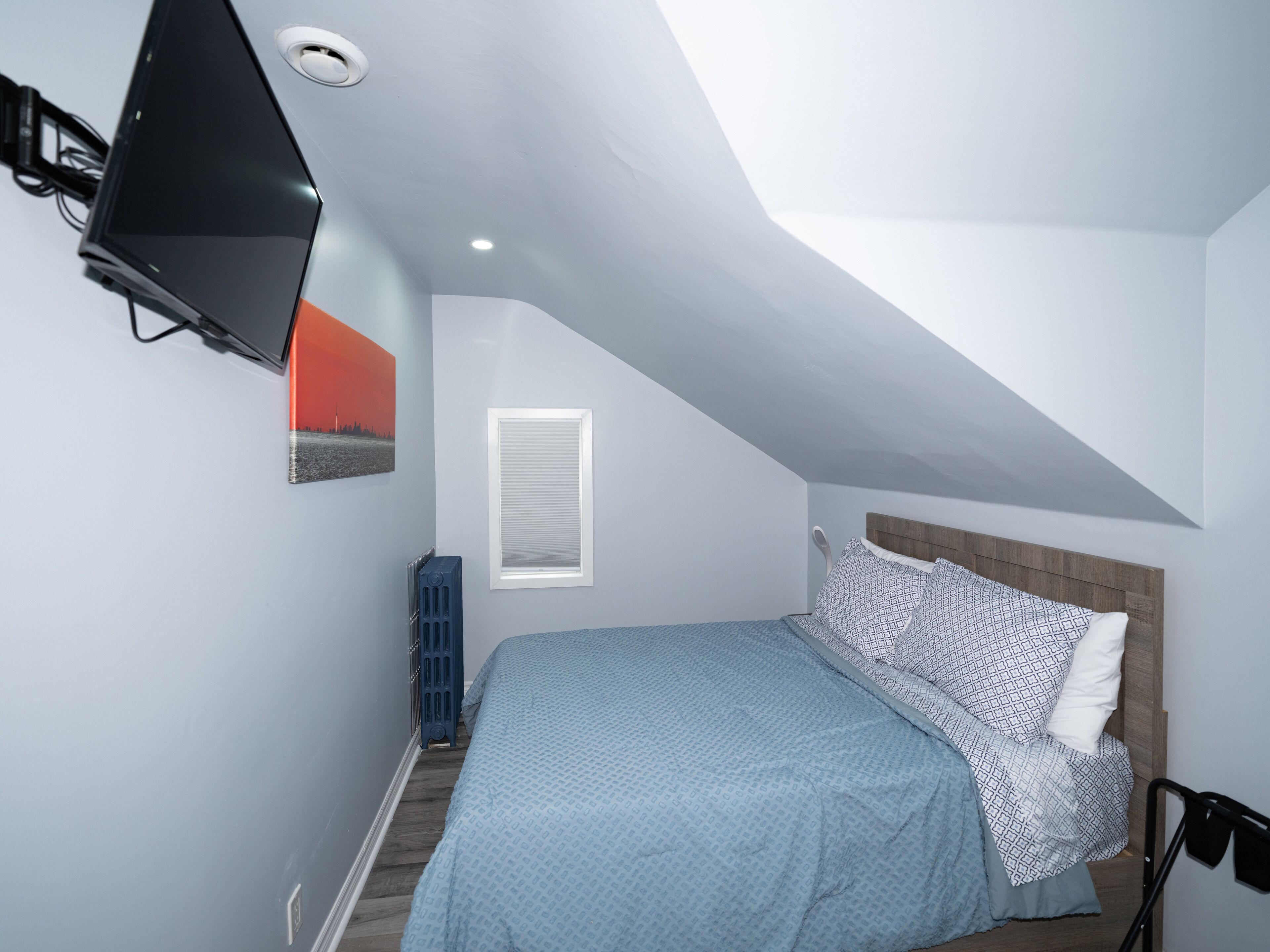 A bedroom with a bed, a window, a radiator, and a ceiling fan.