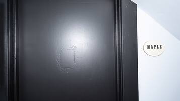 A black door with a metal handle and a circular sign with the word 'MAPLE' on it.