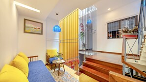 Una sala de estar moderna con un sofá azul, cojines amarillos, una mesa de centro de madera y una alfombra estampada.