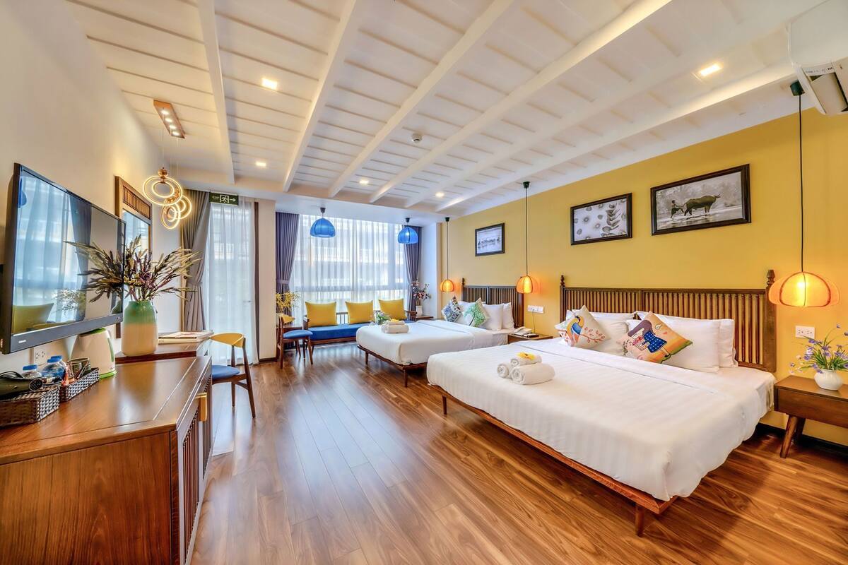Een hotelkamer met twee bedden, een bureau, een televisie en een zithoek met uitzicht.