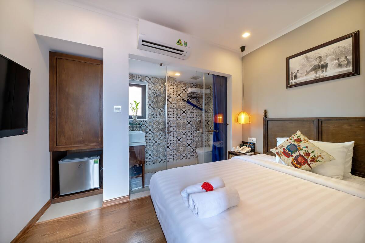 Een hotelkamer met een bed, een kleine koelkast, een douche en een tv aan de muur.