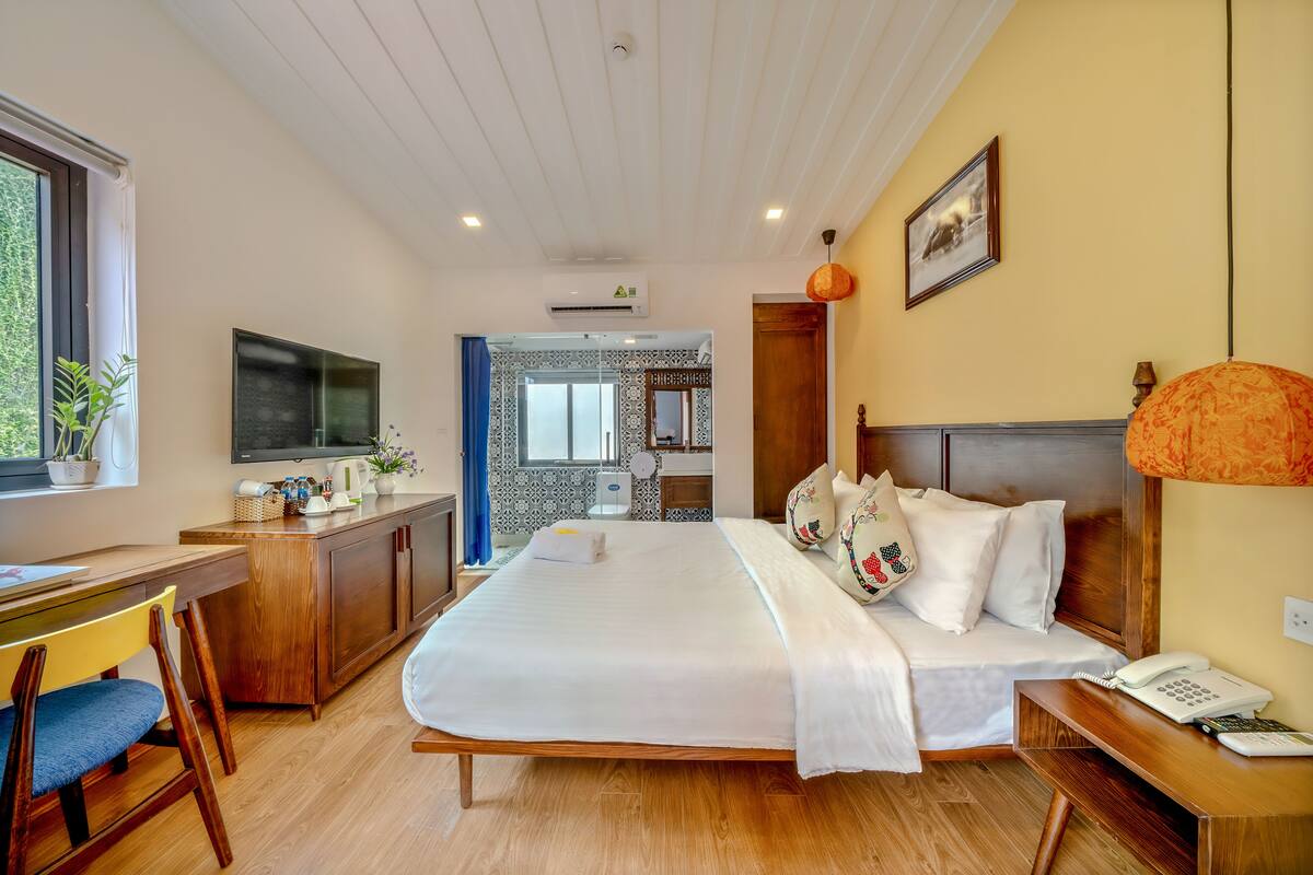 Een hotelkamer met een groot bed, houten meubels, een bureau en een televisie.