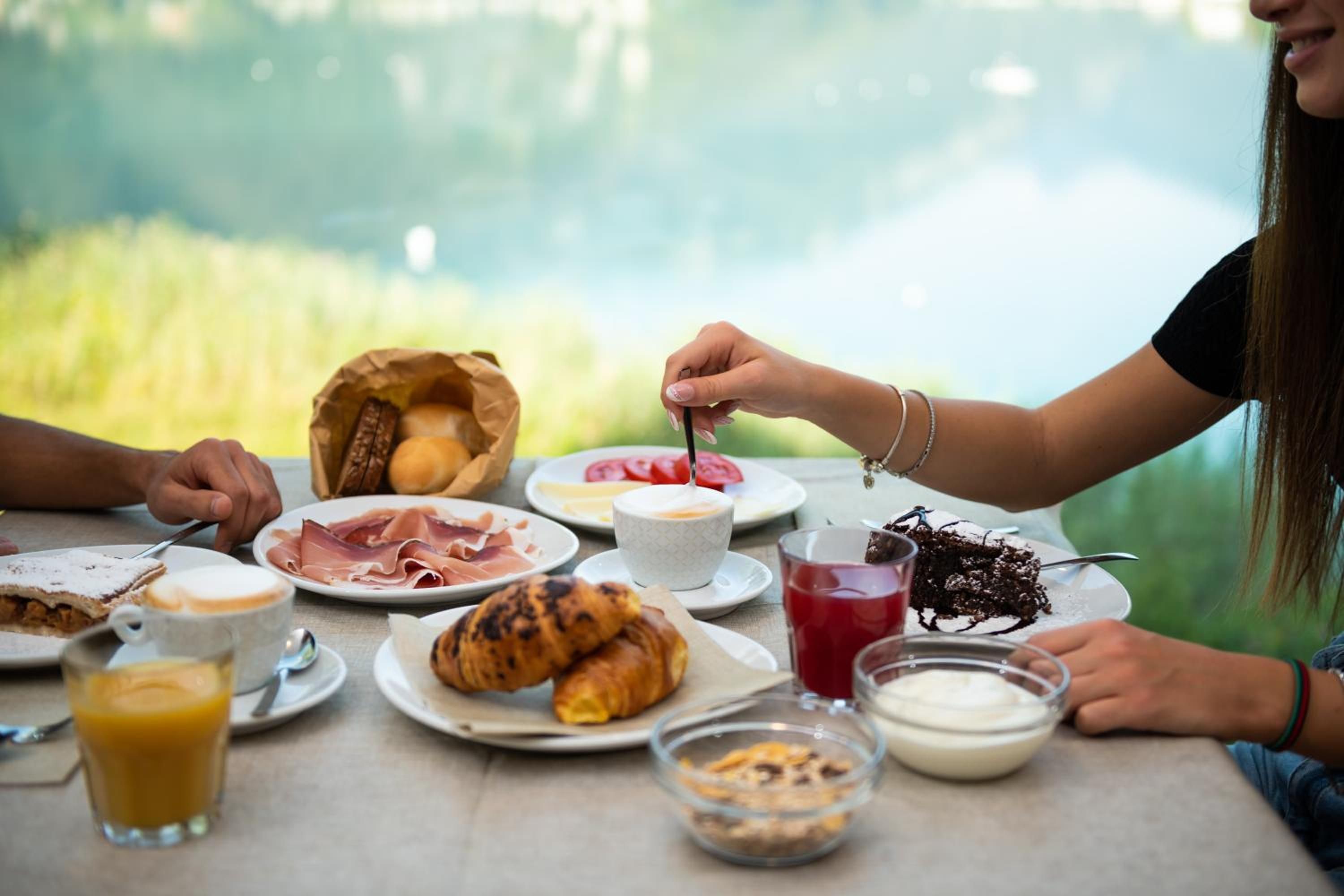 Impostazione colazione con croissant, prosciutto e un croissant in un sacchetto di carta.