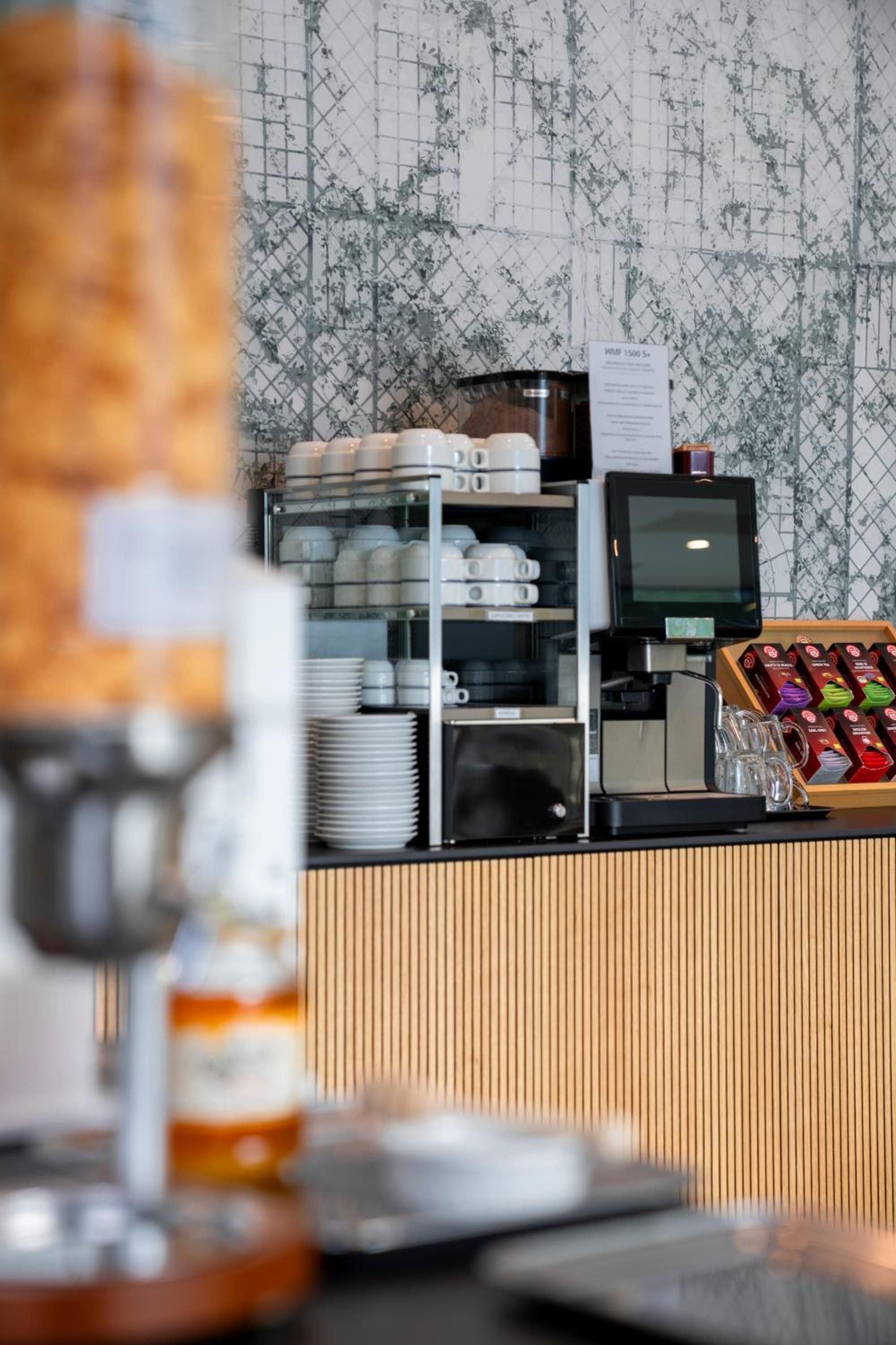 Angolo caffè con macchina da caffè, esposizione di tazze e cartello con il menù.