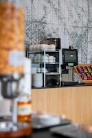 Angolo caffè con macchina da caffè, esposizione di tazze e cartello con il menù.