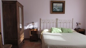 A bedroom with a bed, a nightstand, a dresser, a mirror, and a painting on the wall. - Hostal de la Luz (Cuenca)