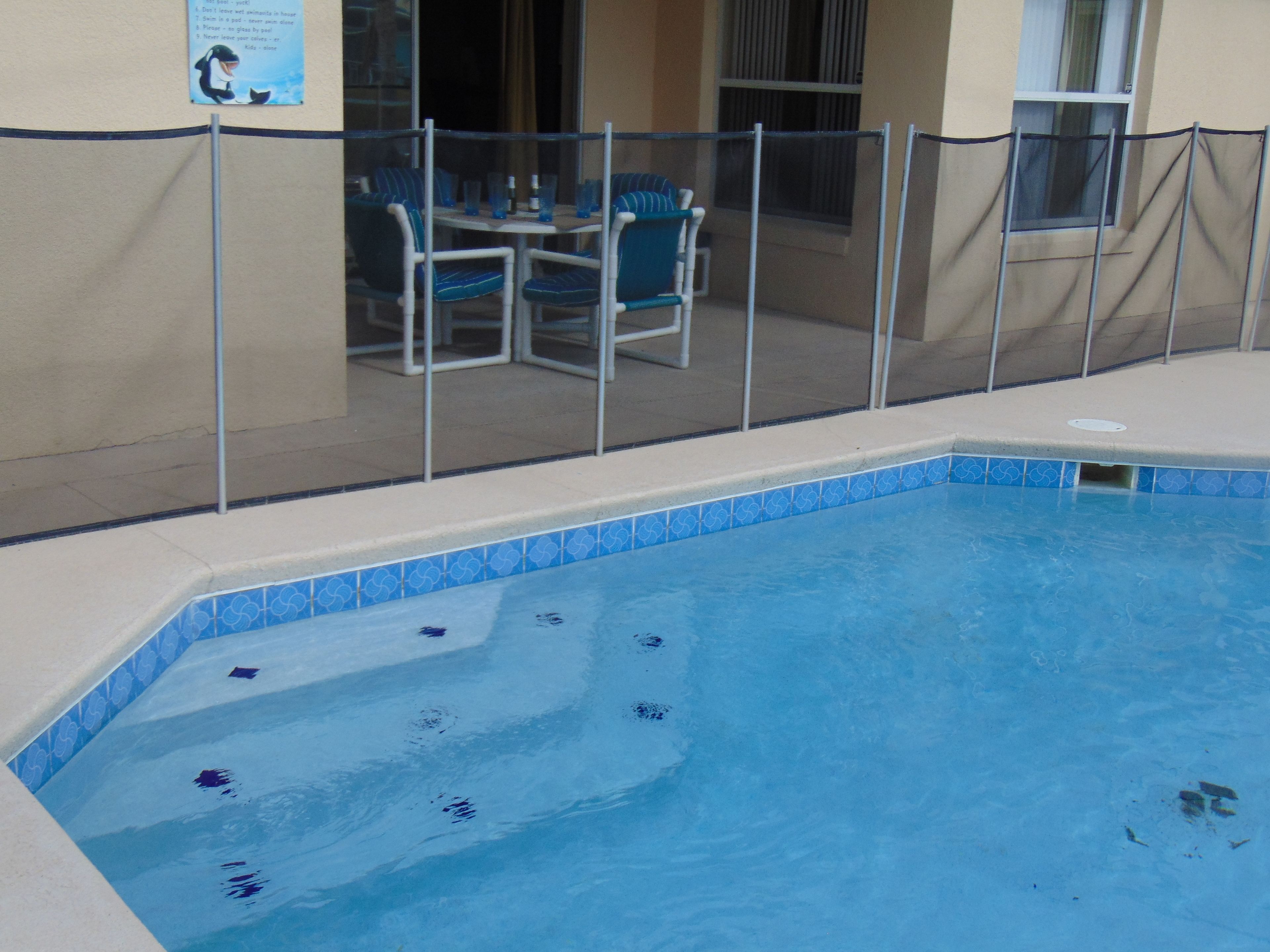 En swimmingpool med flisekant, omgivet af et gelænder.