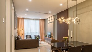 A modern living room with a sofa, chairs, a dining table, and a TV.