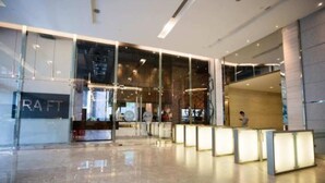 A modern lobby with glass partitions, a reception desk, and a staircase.