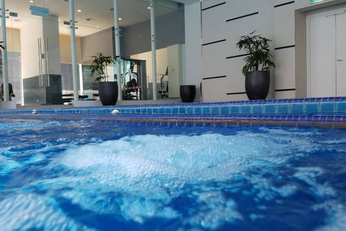 An indoor swimming pool with clear water, surrounded by modern architecture and potted plants.