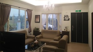 Una sala de estar con sofá, una mesa de centro, televisor y candelabro.
