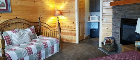 A cozy room with a wooden bed, a fireplace, a lamp, and a microwave.