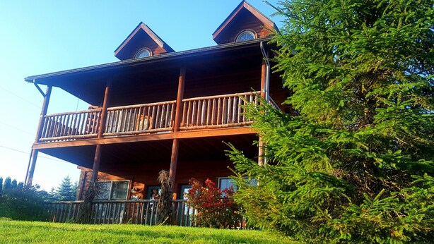 A wooden cabin with a balcony, surrounded by greenery. - Amish Blessings Cabins (Berlin)