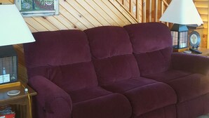 A wooden interior with a purple sofa, a staircase, and framed pictures on the walls. - Amish Blessings Cabins (Berlin)