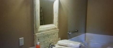 A bathroom with a sink, mirror, faucet, and a bathtub.
