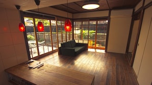 Une pièce avec un plancher en bois, un canapé, une table en bois et une grande fenêtre donnant sur un paysage verdoyant.