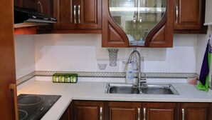 Une cuisine avec des meubles de rangement en bois, un évier en acier inoxydable et un four encastré.