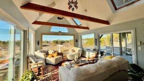 Uma sala de estar espaçosa com uma cama grande, vários espaços de estar e janelas amplas com vista para o exterior.