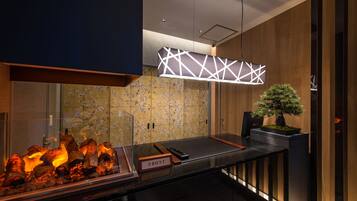 A modern kitchen with a built-in grill, a wooden backsplash, and a minimalist pendant light.