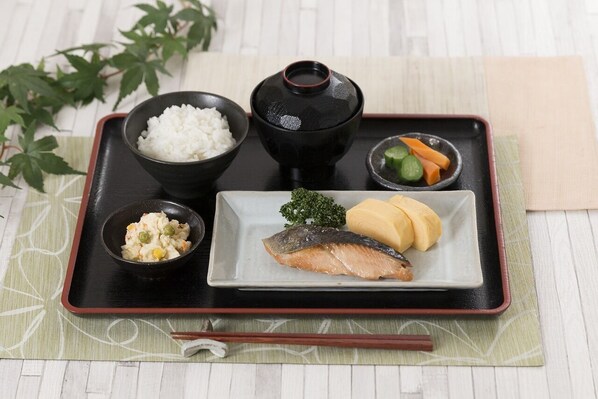 Un plateau avec du riz, un bol de soupe miso, un morceau de poisson et des légumes marinés.
