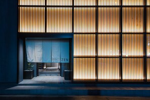 L’entrée d’un hôtel au design moderne, caractérisée par des lambris en bois verticaux et une enseigne bien visible indiquant « HÔTEL ZEN ».
