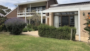 A two-story house with a balcony, a covered patio, and a garden with lavender and other plants. - Banksia Park Estate (Newhaven)