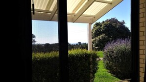 A covered outdoor area with a view of a garden and a distant landscape. - Banksia Park Estate (Newhaven)