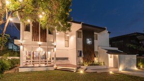 A modern two-story house with a well-lit entrance, a visible sign, and a small outdoor seating area. - The Mellow Pillow at Chiang Mai Gate (Chiang Mai)