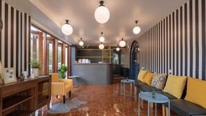 A modern interior with striped walls, a reception desk, a sofa, and a wooden floor. - The Mellow Pillow at Chiang Mai Gate (Chiang Mai)