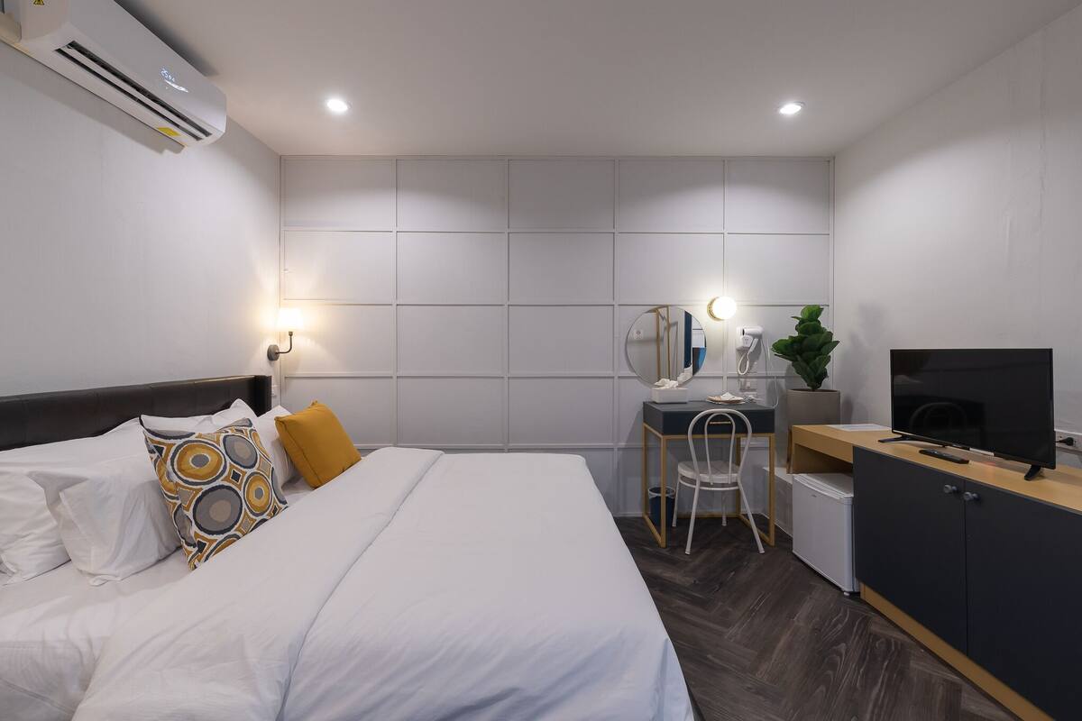 Una habitación de hotel moderna con cama, escritorio y televisor.