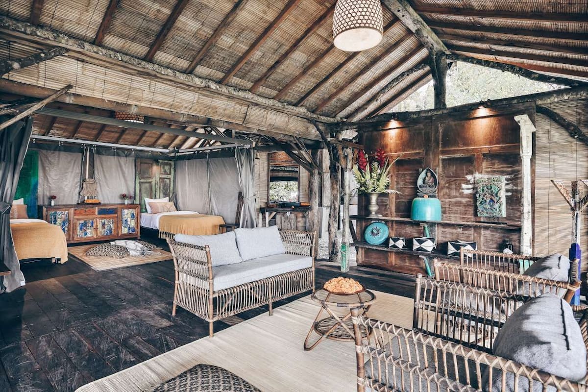 A rustic room with a high ceiling, wicker furniture, and a wooden shelf with decorative items.