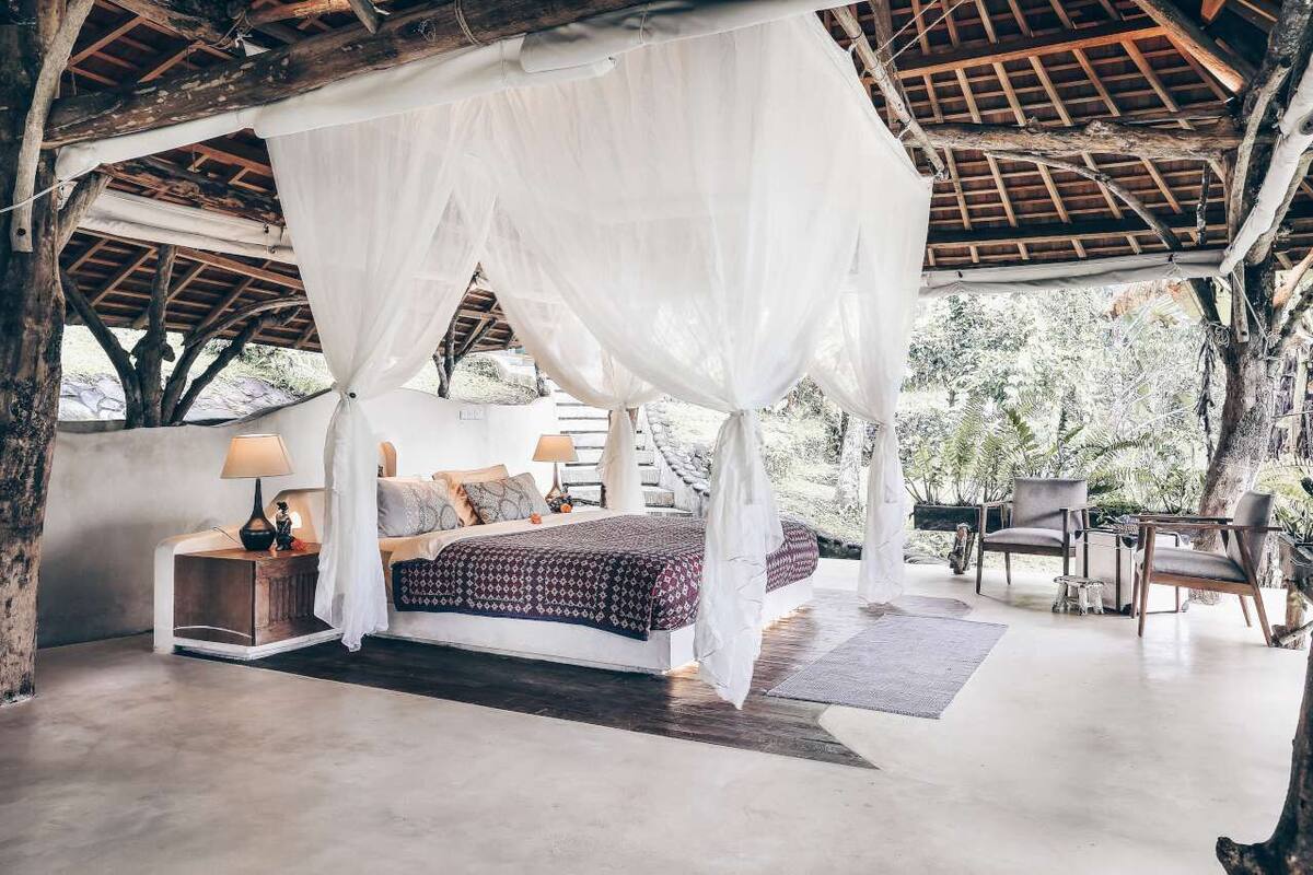 A bedroom with a canopy bed, bedside lamps, and a view of the outdoors.