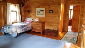 Un dormitorio de cabaña de madera con cama, cómoda y un cuadro en la pared.