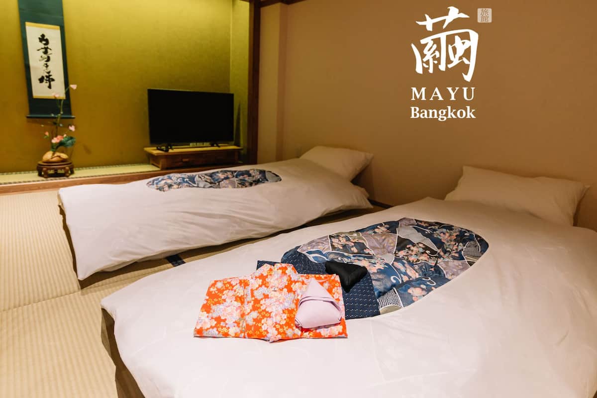 A hotel room with two beds, a television, and a traditional Japanese decor.