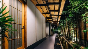 A corridor with a wooden door, a tiled ceiling, and a water feature with plants. - MAYU Bangkok Japanese Style Hotel (Bangkok)