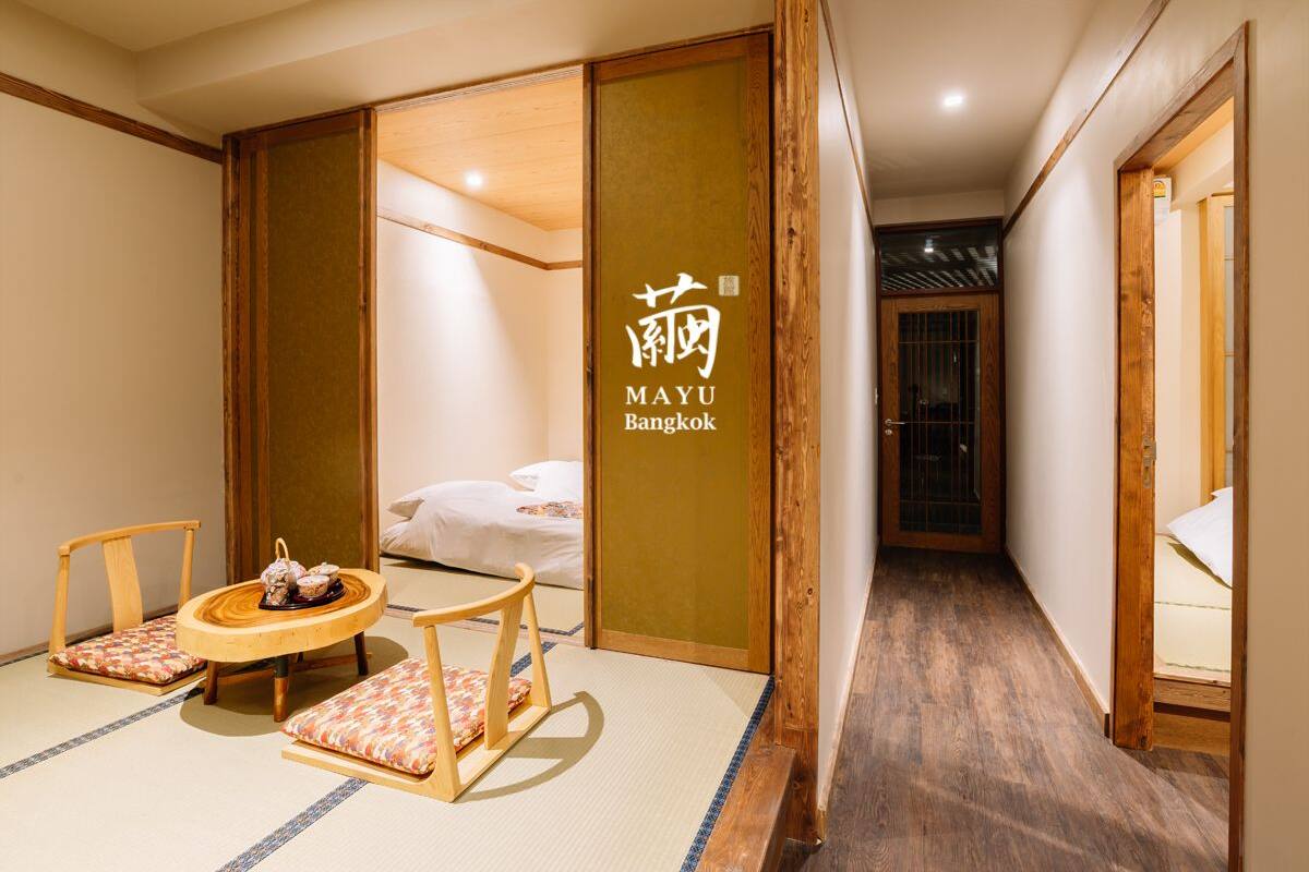 A traditional Japanese-style room with tatami flooring, a low wooden table with a tea set, and a bed with white bedding.
