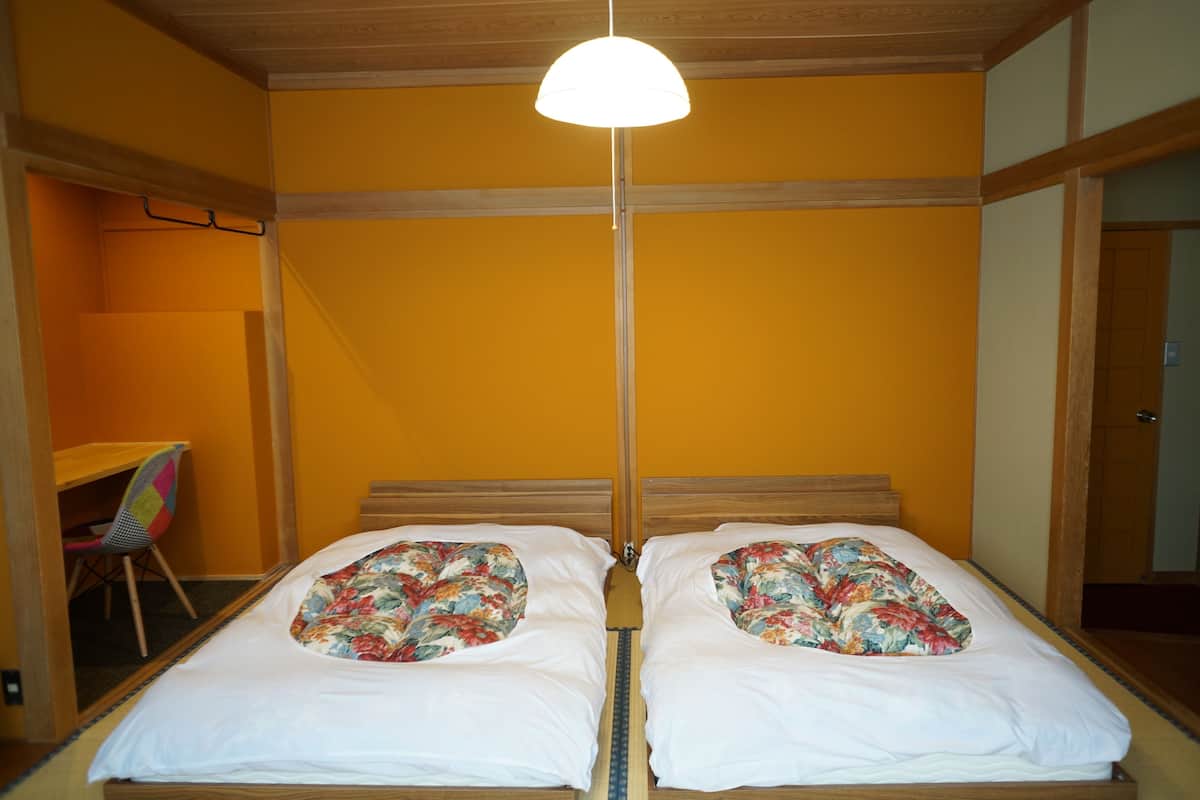 A room with two beds, a desk, and a chair.