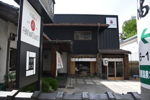 A building with a sign for 'Hostel & Spa FUN! MATSUMOTO' and a sign indicating room numbers 6-1. - Hostel & Spa FAN! MATSUMOTO (Matsumoto)