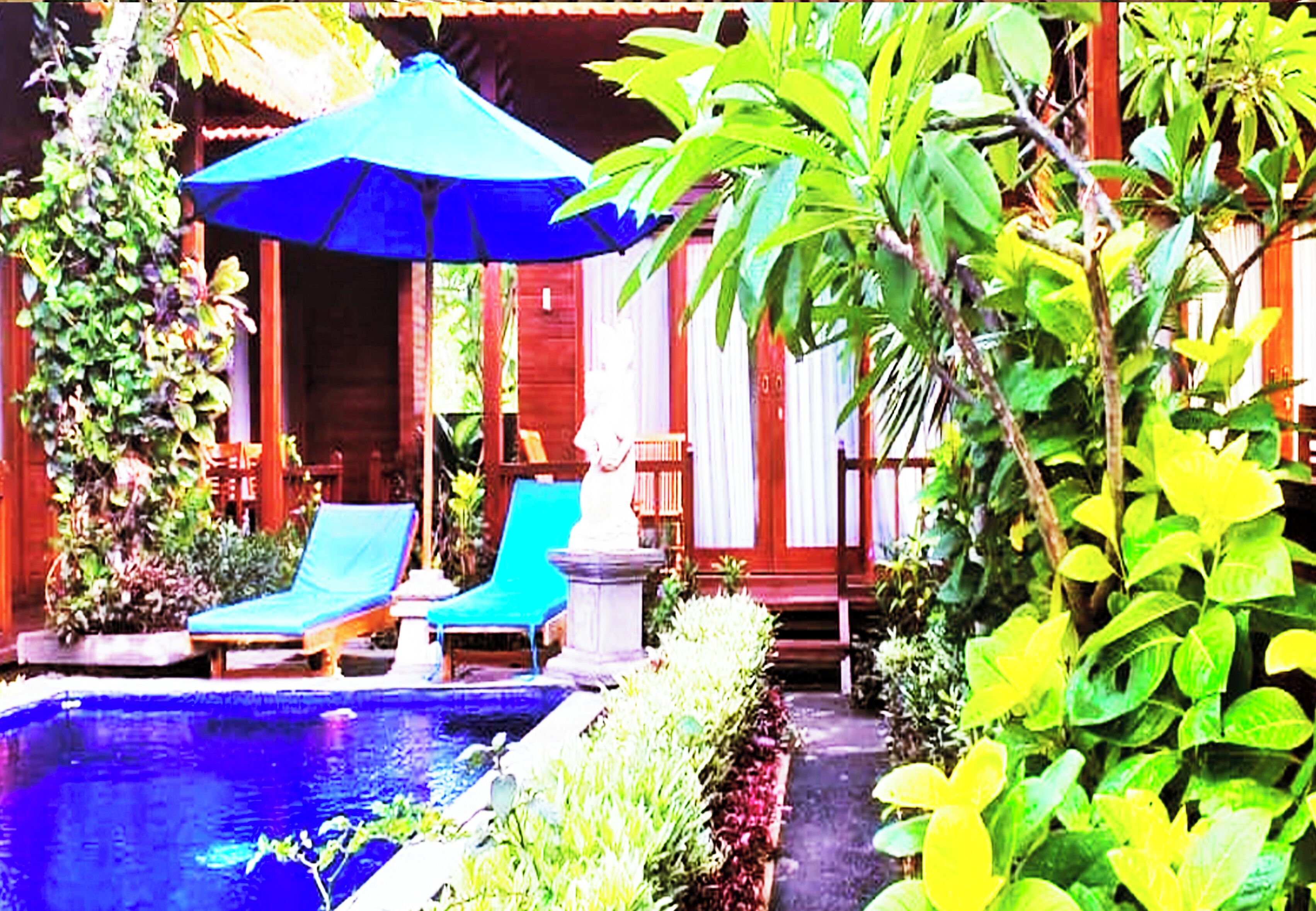 A pool area with lounge chairs and a blue umbrella.