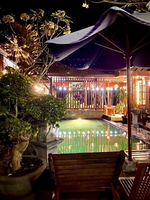 An outdoor pool area with a wooden deck, potted plants, and a covered seating area. - Wait Garden Cottage (Penida Island)