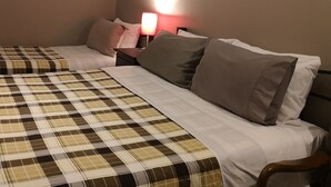 A hotel room with a bed, a nightstand, a lamp, and a painting on the wall.