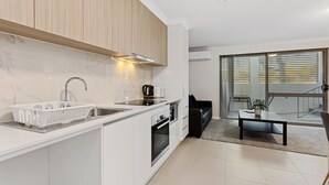 Una cucina moderna con forno integrato, lavello e macchina da caffè. C'è un'area pranzo con tavolo e sedie.