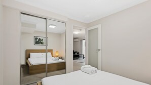 Una camera d'hotel con un letto, una lampada da comodino, uno specchio e una porta che dà su un'altra stanza.