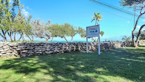 A stone wall with a sign for 'Minne Cottages'. - Ixora West - Views over Elizabeth harbor, beach access across the road. (George Town)