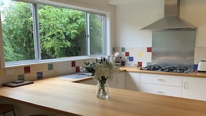 Una cocina moderna con un amplio ventanal, una campana extractora de acero inoxidable y una encimera de madera.