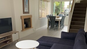 Una sala de estar moderna con un sofá azul oscuro, un televisor de pantalla plana y una pequeña mesa blanca.