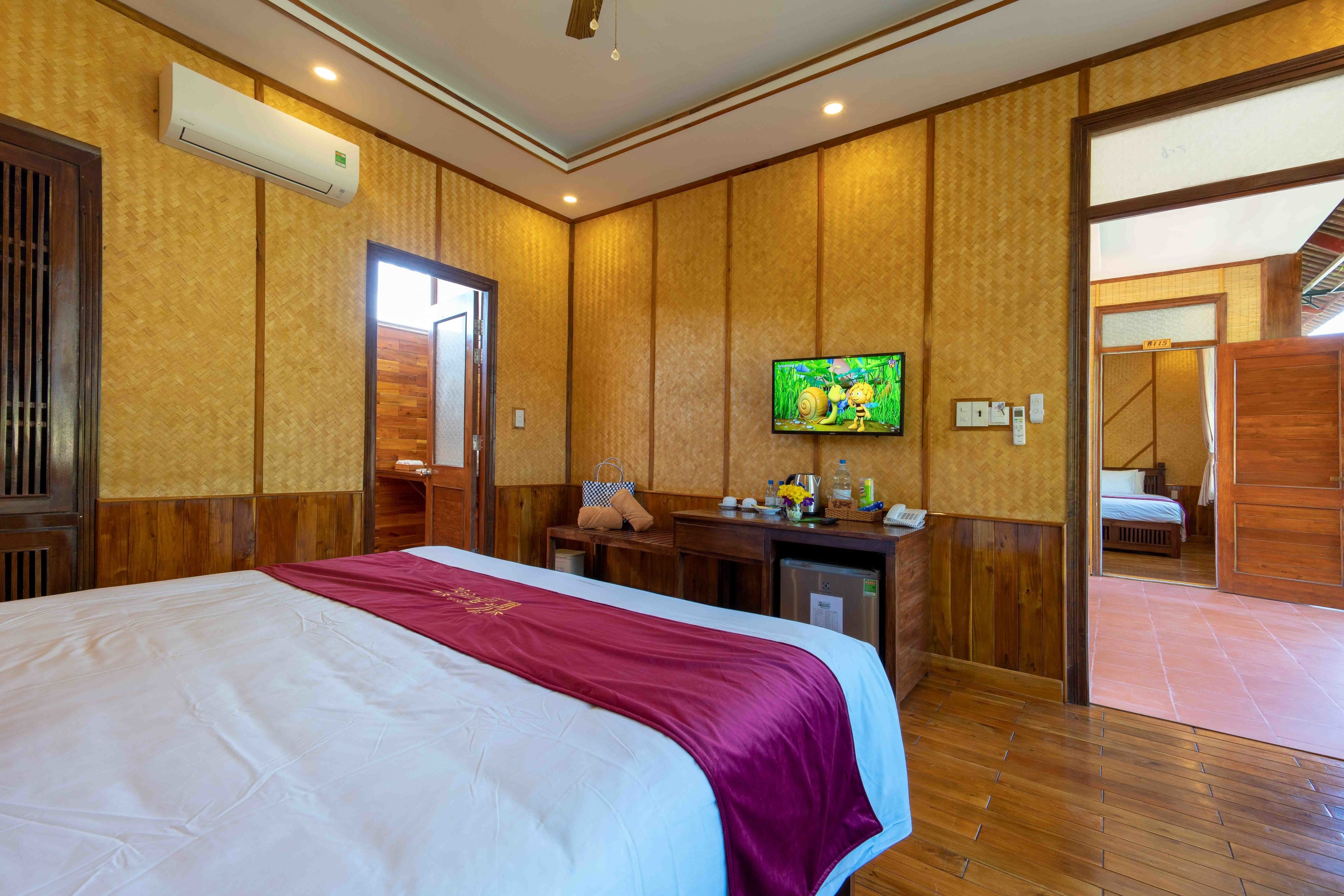 A hotel room with a large bed, a television, a wooden desk, and a mirror.
