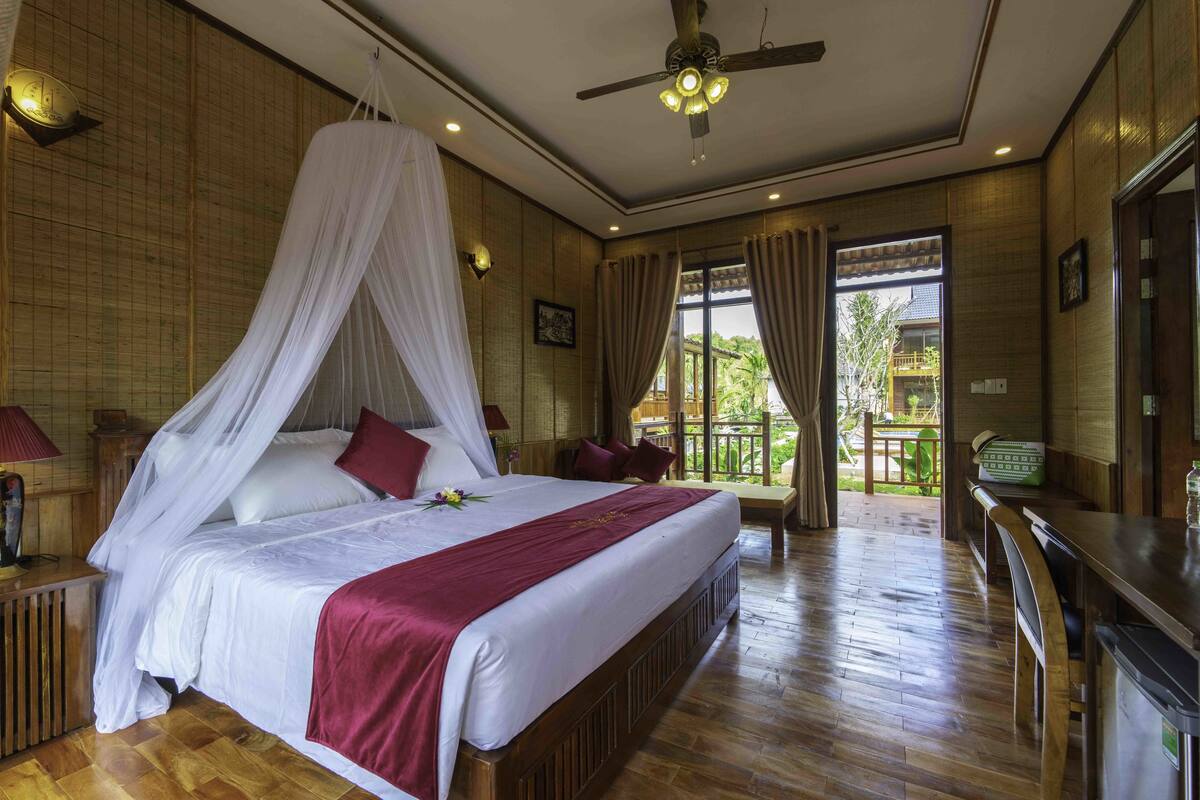 A spacious bedroom with a large bed, a ceiling fan, and a view of the outdoors.