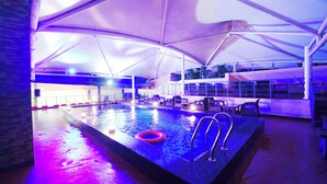 Piscina interna com toldo, cadeiras de descanso e boia.