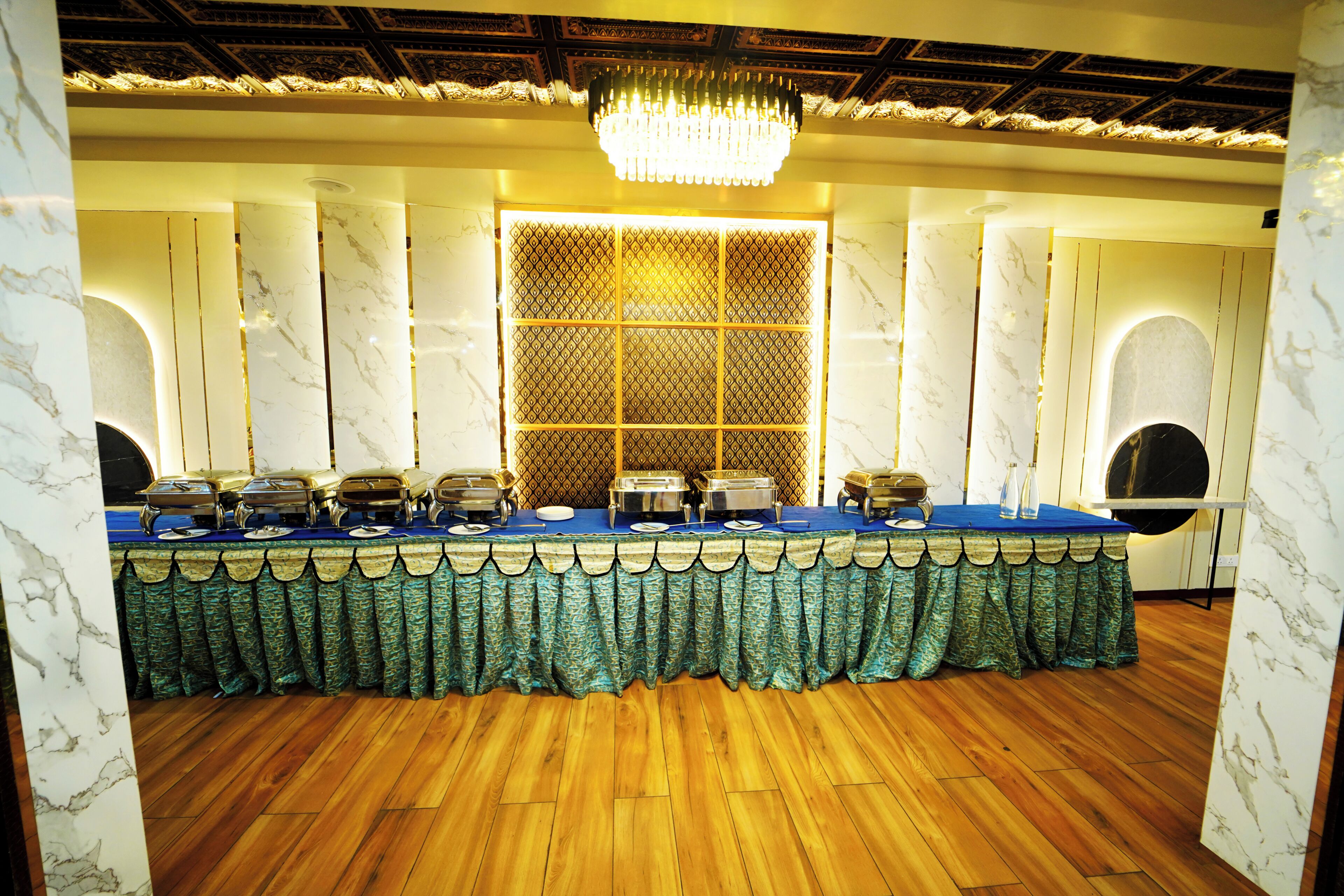 A banquet hall with a long table, chandeliers, and marble walls.